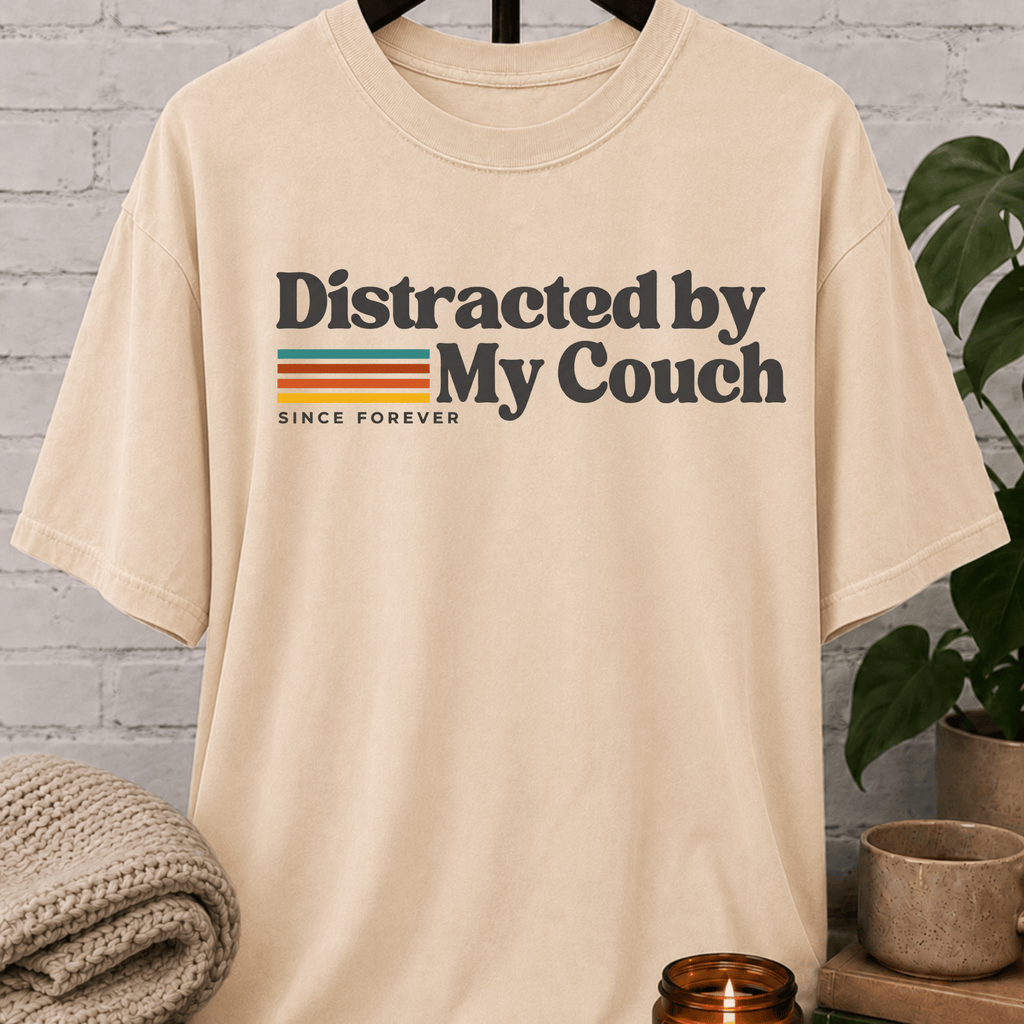 Funny homebody T-shirt featuring “Distracted by My Couch Since Forever” with retro stripes, a couch potato graphic tee for stay-home lovers and indoorsy people.