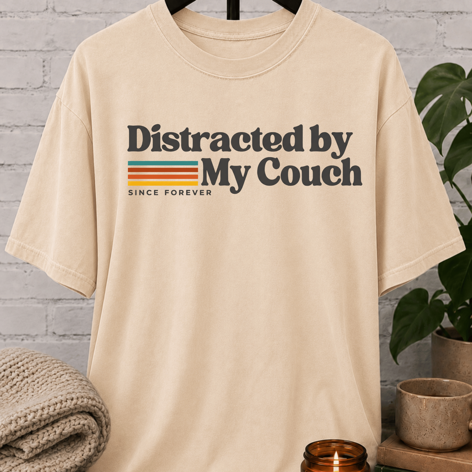 Funny homebody T-shirt featuring “Distracted by My Couch Since Forever” with retro stripes, a couch potato graphic tee for stay-home lovers and indoorsy people.