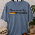 Funny homebody T-shirt featuring “Distracted by My Couch Since Forever” with retro stripes, a couch potato graphic tee for stay-home lovers and indoorsy people.