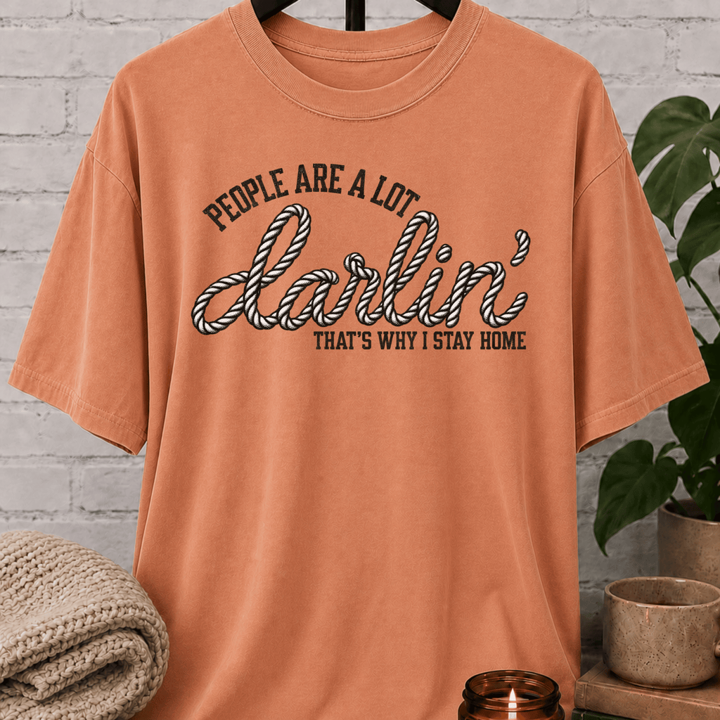 Western homebody T-shirt featuring rope-style lettering and the phrase “People Are a Lot Darlin’ That’s Why I Stay Home,” a funny sarcastic graphic tee for introverts, antisocial personalities, and stay-home lovers.