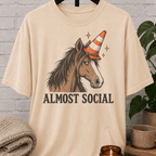 Funny horse introvert T-shirt featuring an unimpressed horse wearing an orange traffic cone with the phrase “Almost Social,” a quirky graphic tee for socially awkward homebodies and low social battery humor fans.
