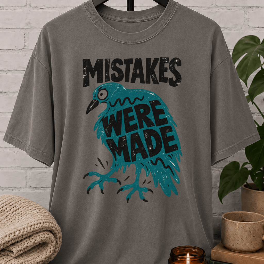 Funny crow graphic T-shirt featuring a frazzled teal bird with the phrase “Mistakes Were Made,” a sarcastic overthinker shirt for socially awkward humor and relatable mistake lovers.