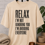 Funny antisocial T-shirt featuring the phrase “Relax I’m Not Ignoring You I’m Avoiding Everyone,” a sarcastic graphic tee for loners, introverts, socially selective people, and fans of people-avoidance humor.