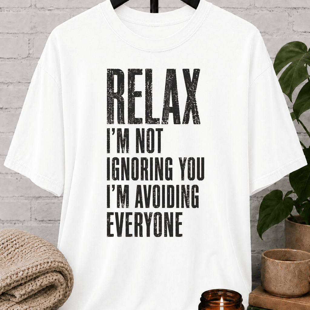 Funny antisocial T-shirt featuring the phrase “Relax I’m Not Ignoring You I’m Avoiding Everyone,” a sarcastic graphic tee for loners, introverts, socially selective people, and fans of people-avoidance humor.