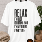 Funny antisocial T-shirt featuring the phrase “Relax I’m Not Ignoring You I’m Avoiding Everyone,” a sarcastic graphic tee for loners, introverts, socially selective people, and fans of people-avoidance humor.
