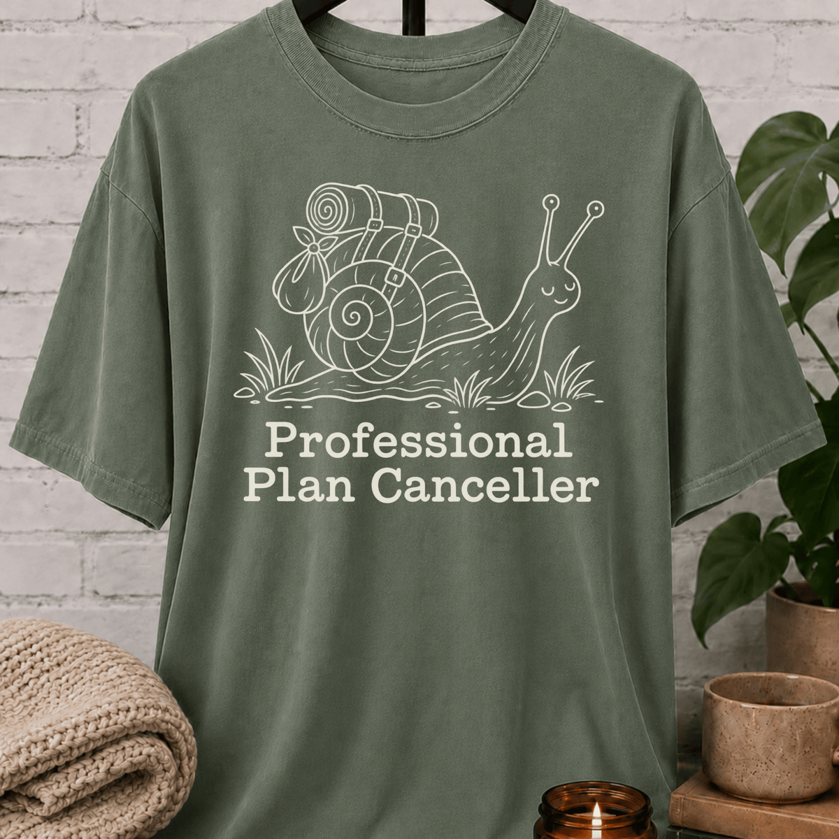 Funny introvert snail T-shirt featuring a backpacking snail with the phrase “Professional Plan Canceller,” a cancel plans graphic tee for low social battery, socially selective, and introvert humor fans.