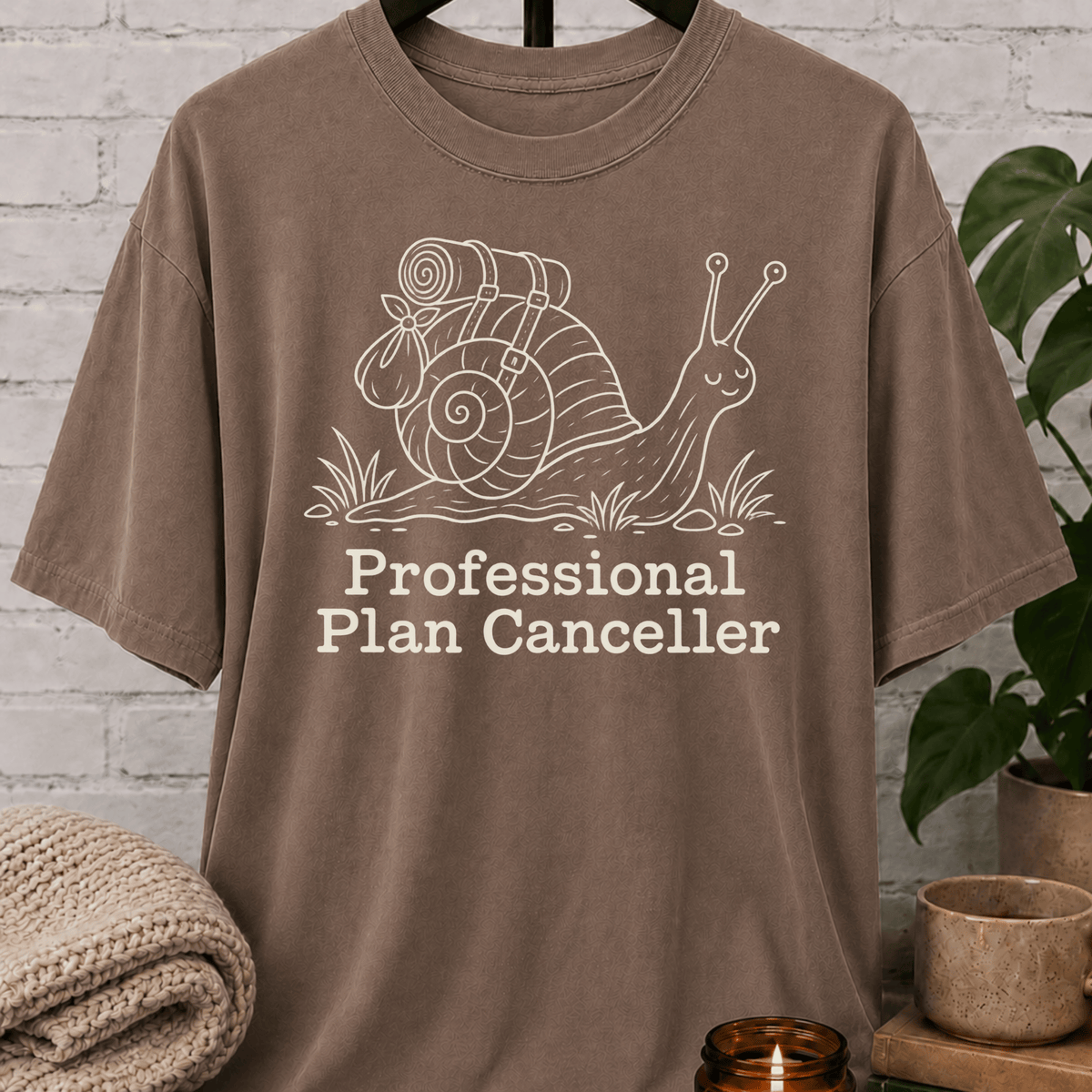 Funny introvert snail T-shirt featuring a backpacking snail with the phrase “Professional Plan Canceller,” a cancel plans graphic tee for low social battery, socially selective, and introvert humor fans.