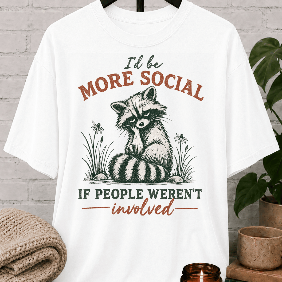 Funny raccoon graphic T-shirt featuring a vintage raccoon and the phrase “I’d Be More Social If People Weren’t Involved,” a sarcastic antisocial shirt for socially selective people and fans of avoid-people humor.
