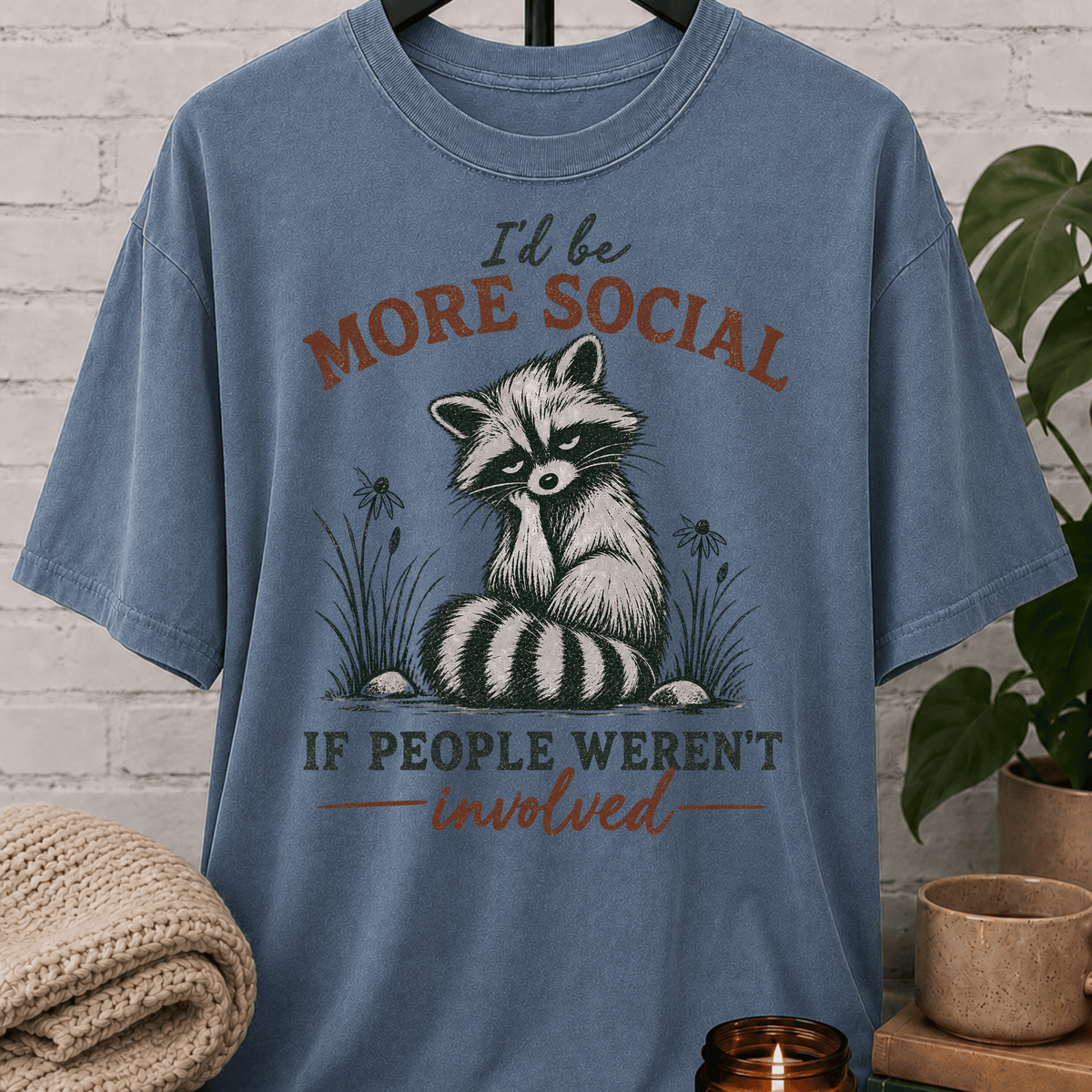 Funny raccoon graphic T-shirt featuring a vintage raccoon and the phrase “I’d Be More Social If People Weren’t Involved,” a sarcastic antisocial shirt for socially selective people and fans of avoid-people humor.