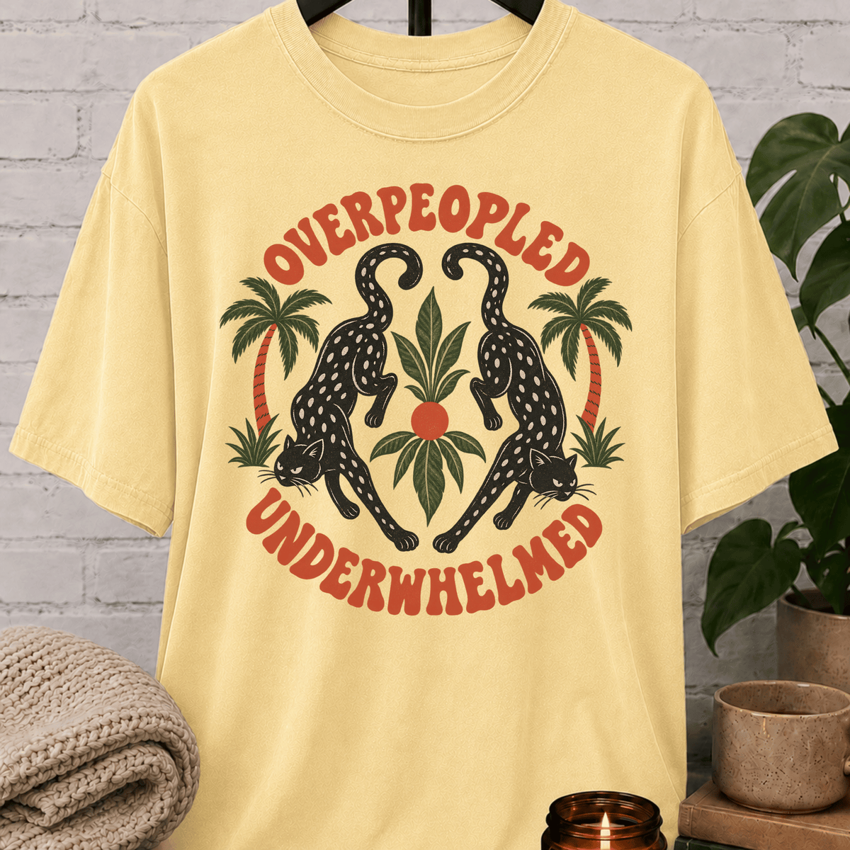 Antisocial leopard T-shirt featuring two black leopards, palm trees, tropical leaves, and the phrase “Overpeopled Underwhelmed,” a funny graphic tee for loners, socially drained people, and sarcastic people-avoidance humor fans.
