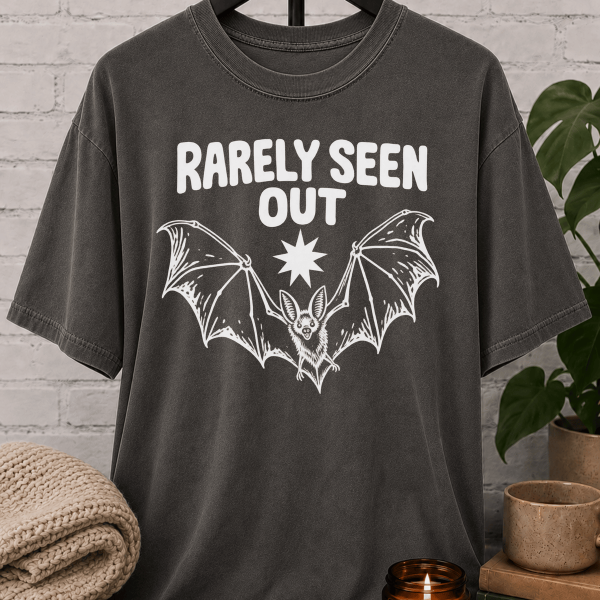 Hermit bat graphic T-shirt featuring a vintage flying bat and the phrase “Barely Seen Out,” an indoorsy graphic tee for reclusive types, loners, and people who prefer staying out of sight.