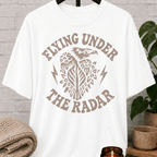 Loner eagle graphic T-shirt featuring a vintage flying eagle, lightning bolt accents, and the phrase “Flying Under the Radar,” a low-profile shirt for private people and fans of sarcastic solitude humor.