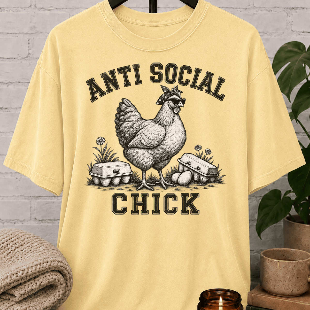 Antisocial chicken graphic T-shirt featuring a hen in sunglasses and a bandana with eggs and the phrase “Anti Social Chick,” a sarcastic farm animal shirt for socially selective humor fans.