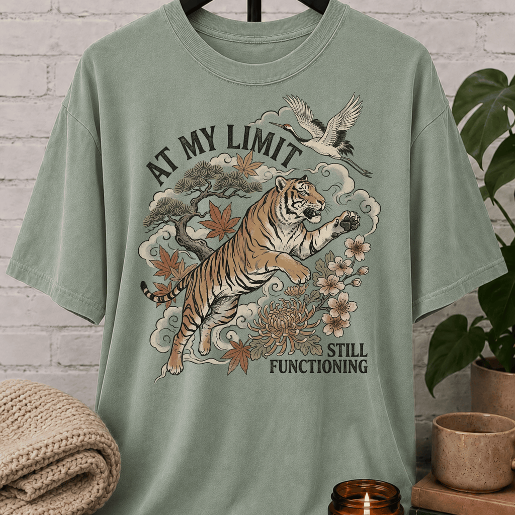 Overstimulated tiger graphic T-shirt featuring a leaping tiger with floral artwork, cranes, and the phrase “At My Limit Still Functioning,” a sarcastic graphic tee for overthinkers, overwhelmed people, and anxious humor fans.