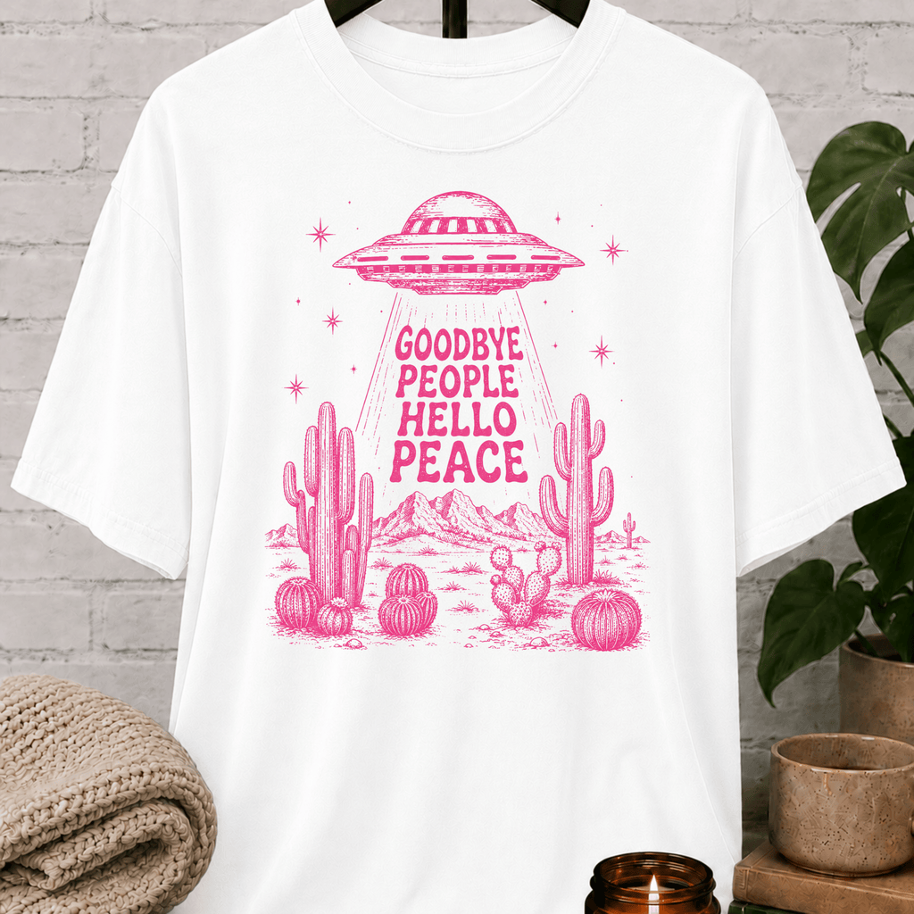 Antisocial alien UFO T-shirt featuring a pink flying saucer hovering above desert cacti with the phrase “Goodbye People Hello Peace,” a sarcastic graphic tee for loners and people who prefer solitude.