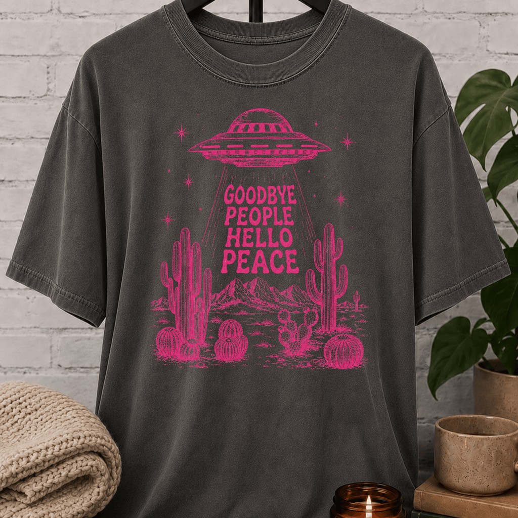 Antisocial alien UFO T-shirt featuring a pink flying saucer hovering above desert cacti with the phrase “Goodbye People Hello Peace,” a sarcastic graphic tee for loners and people who prefer solitude.
