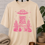 Antisocial alien UFO T-shirt featuring a pink flying saucer hovering above desert cacti with the phrase “Goodbye People Hello Peace,” a sarcastic graphic tee for loners and people who prefer solitude.