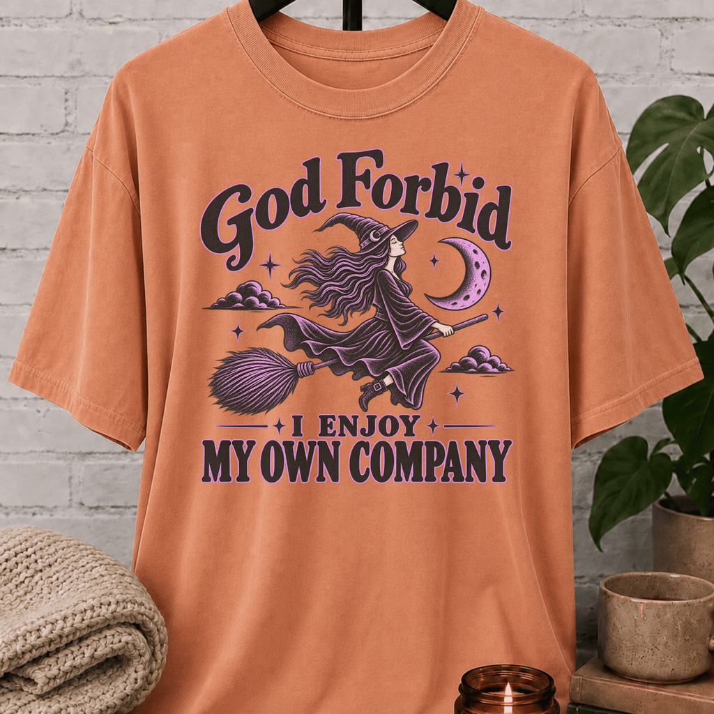 Witch graphic T-shirt featuring a flying witch on a broom, crescent moon, stars, and the phrase “God Forbid I Enjoy My Own Company,” a sarcastic solitude shirt for loners and independent people.