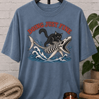 Overthinker black cat graphic T-shirt featuring a black cat riding a fish skeleton through ocean waves with the phrase “Doing Just Fine,” a sarcastic dark humor shirt for overwhelmed people and anxious humor fans.