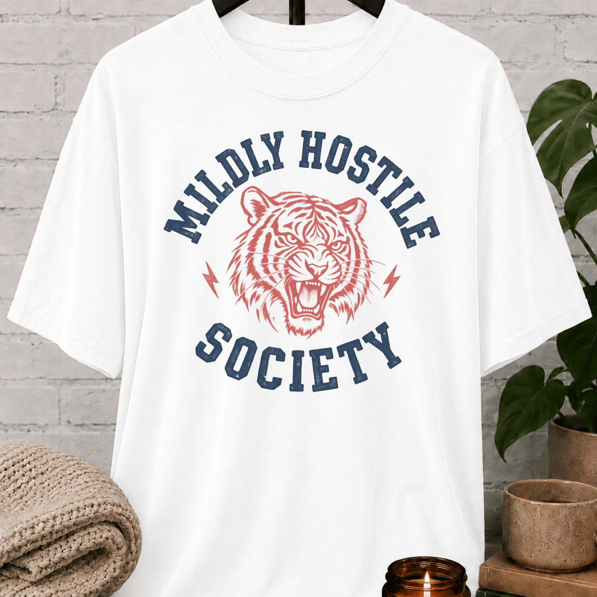 Socially selective tiger graphic T-shirt featuring a snarling tiger, lightning bolt accents, and the phrase “Mildly Hostile Society,” a sarcastic antisocial shirt for people who prefer fewer conversations and more personal space.
