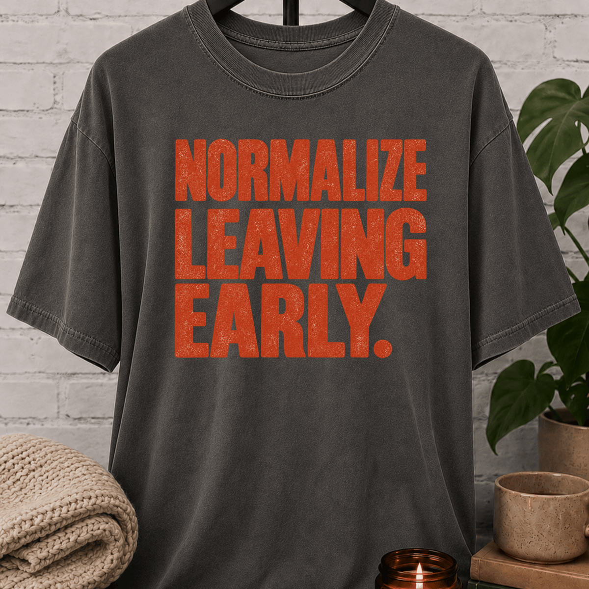 Socially selective graphic T-shirt featuring bold distressed lettering that reads “Normalize Leaving Early,” a sarcastic leave-early shirt for low social battery days and people who prefer an early exit.