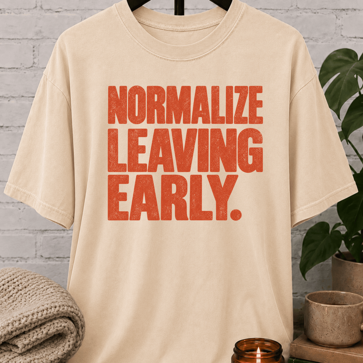 Socially selective graphic T-shirt featuring bold distressed lettering that reads “Normalize Leaving Early,” a sarcastic leave-early shirt for low social battery days and people who prefer an early exit.