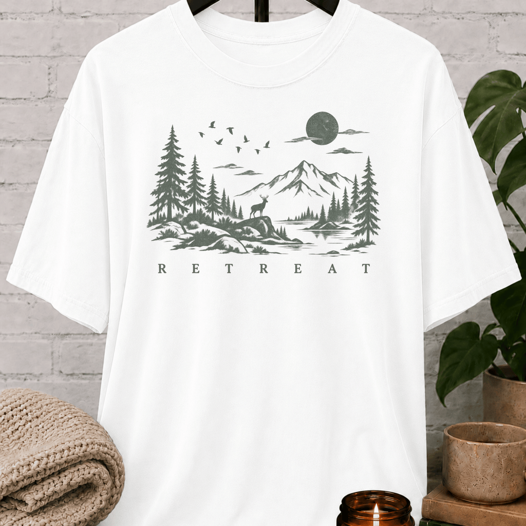 Quiet life nature graphic T-shirt featuring a mountain lake, pine trees, deer, birds, and moon with the word “Retreat,” an outdoorsy solitude shirt for people who recharge alone.