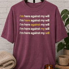 Social obligation graphic T-shirt featuring the repeated phrase “I’m Here Against My Will,” a sarcastic shirt for reluctant attendees, socially selective people, and fans of unwanted plans humor.