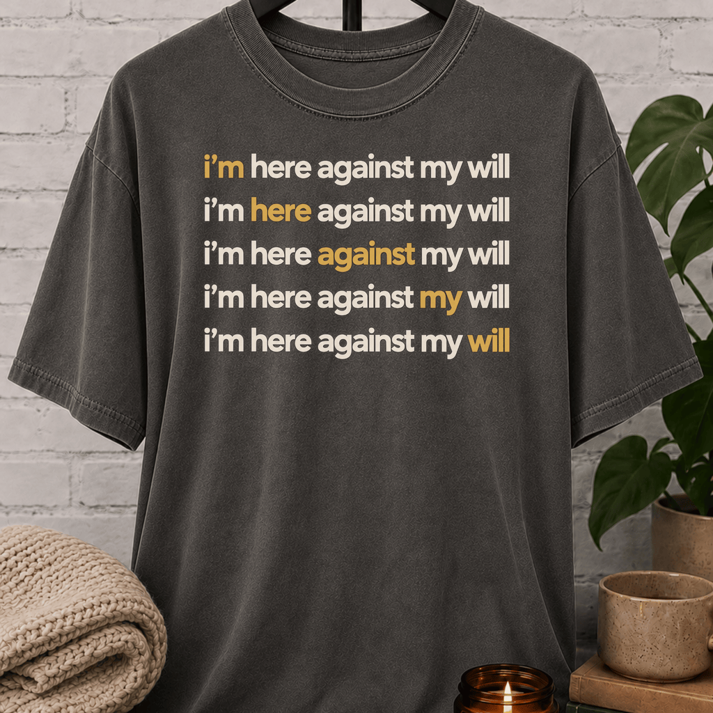 Social obligation graphic T-shirt featuring the repeated phrase “I’m Here Against My Will,” a sarcastic shirt for reluctant attendees, socially selective people, and fans of unwanted plans humor.