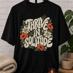 Solitude floral graphic T-shirt featuring retro daisies, poppies, leafy botanical artwork, and the phrase “Thrive in Solitude,” a loner shirt for people who enjoy alone time, quiet living, and their own company.