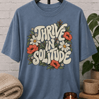 Solitude floral graphic T-shirt featuring retro daisies, poppies, leafy botanical artwork, and the phrase “Thrive in Solitude,” a loner shirt for people who enjoy alone time, quiet living, and their own company.