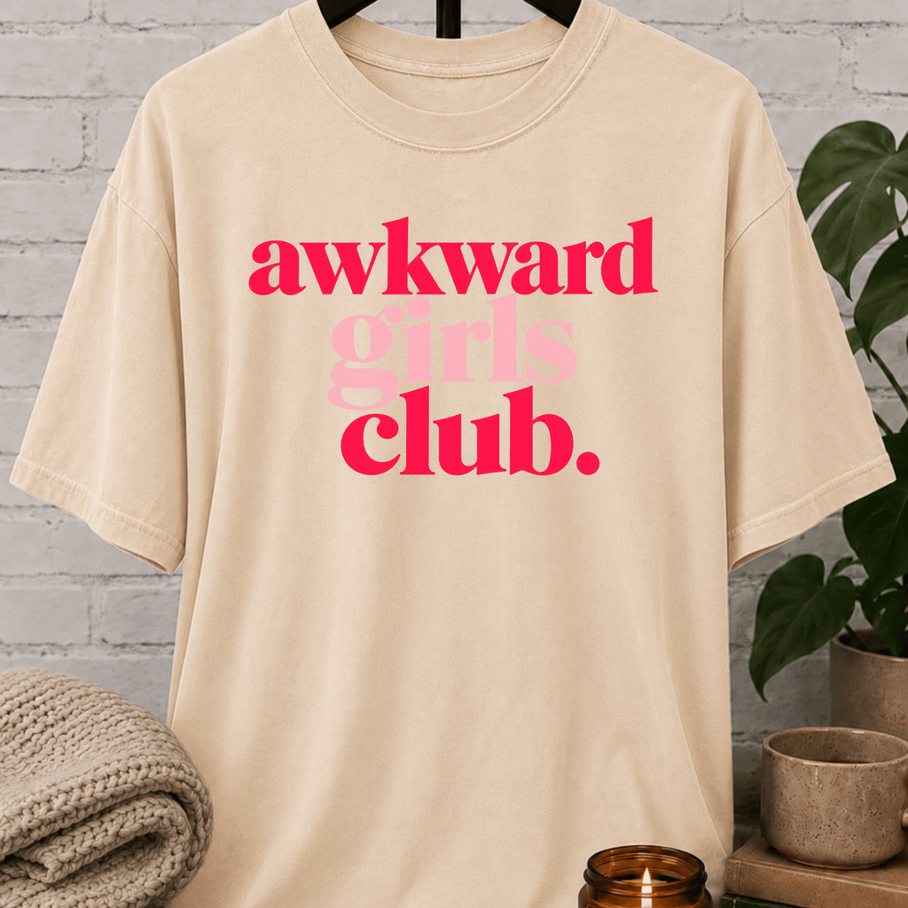 Socially awkward graphic T-shirt featuring the phrase “Awkward Girls Club” in bold retro lettering, an awkward humor shirt for women, shy personalities, and socially clumsy girls.