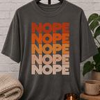 Socially selective graphic T-shirt featuring the word “NOPE” repeated five times in retro stacked lettering, a bold refusal humor shirt for plan avoiders, low social battery days, and people who prefer opting out.