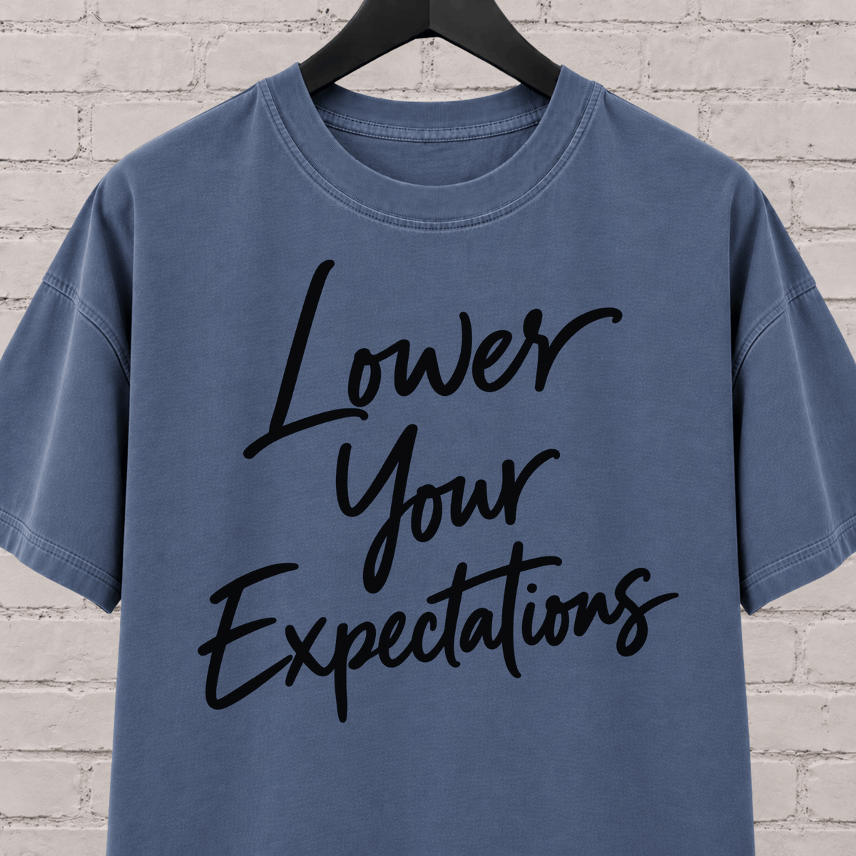 Lower Your Expectations graphic T-shirt featuring bold handwritten lettering, a blunt humor shirt for low-expectation personalities, sarcastic humor fans, and people who prefer keeping the bar low.