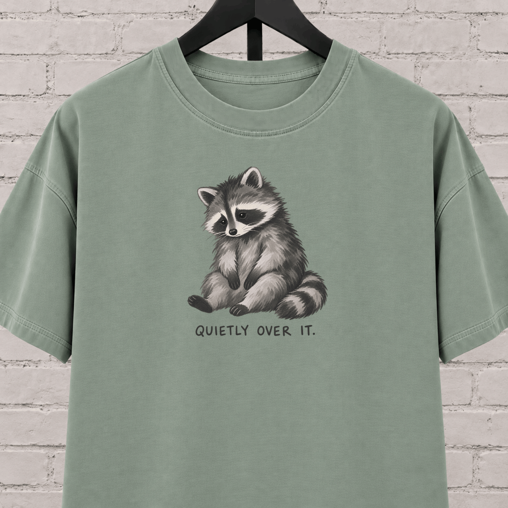 Quietly Over It raccoon graphic T-shirt featuring a tired raccoon, a low social battery shirt for socially drained people and introvert humor fans.