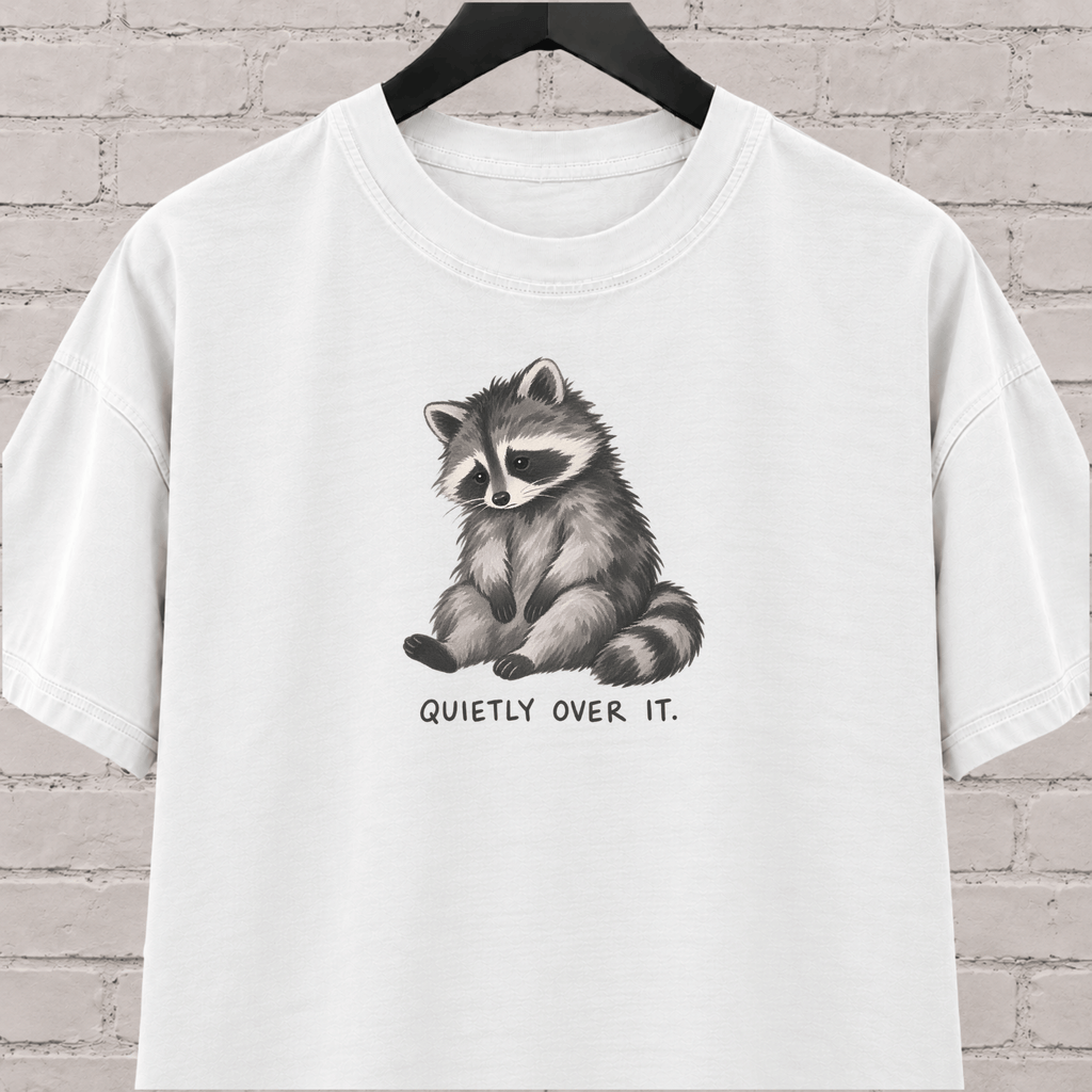 Quietly Over It raccoon graphic T-shirt featuring a tired raccoon, a low social battery shirt for socially drained people and introvert humor fans.