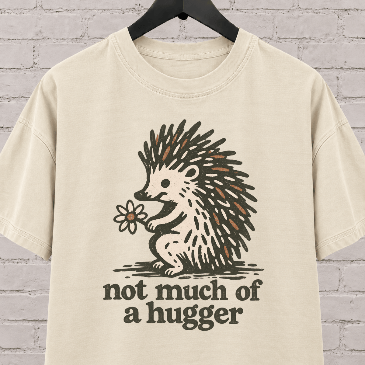 Not Much of a Hugger hedgehog T-shirt featuring a hedgehog holding a flower, an introvert personal space graphic tee.