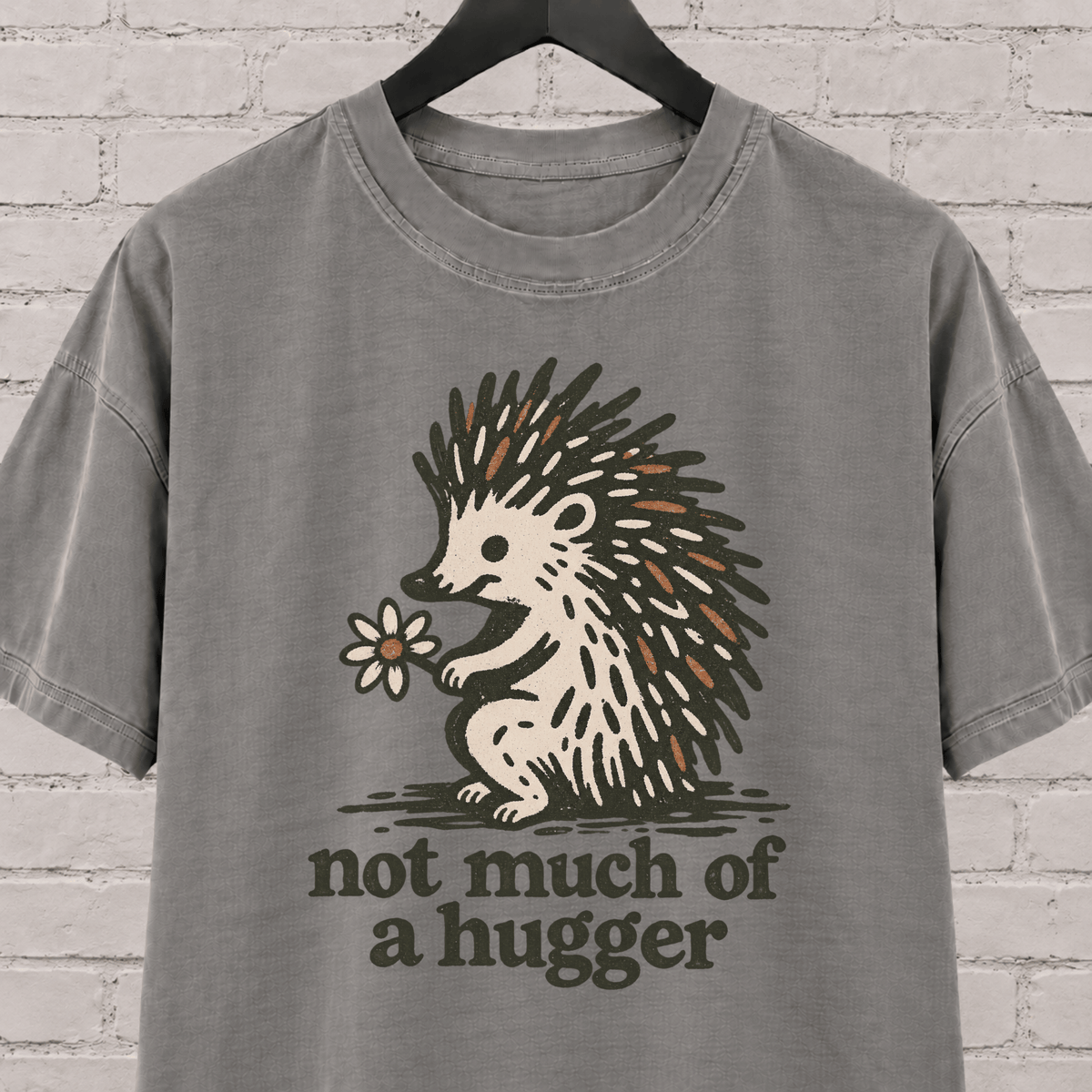 Not Much of a Hugger hedgehog T-shirt featuring a hedgehog holding a flower, an introvert personal space graphic tee.