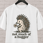 Not Much of a Hugger hedgehog T-shirt featuring a hedgehog holding a flower, an introvert personal space graphic tee.
