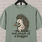 Not Much of a Hugger hedgehog T-shirt featuring a hedgehog holding a flower, an introvert personal space graphic tee.