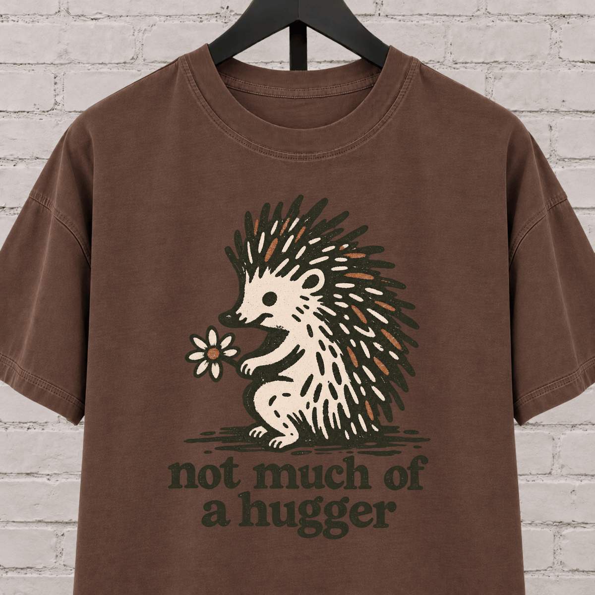 Not Much of a Hugger hedgehog T-shirt featuring a hedgehog holding a flower, an introvert personal space graphic tee.