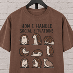 Socially awkward hedgehog graphic T-shirt featuring nine illustrated hedgehogs in different poses with the phrase “How I Handle Social Situations.”